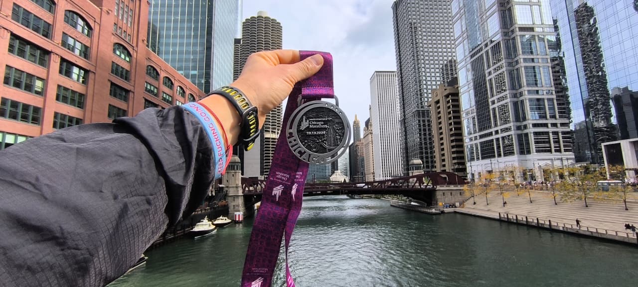 Chicago Marathon finisher medal held over the Chicago River